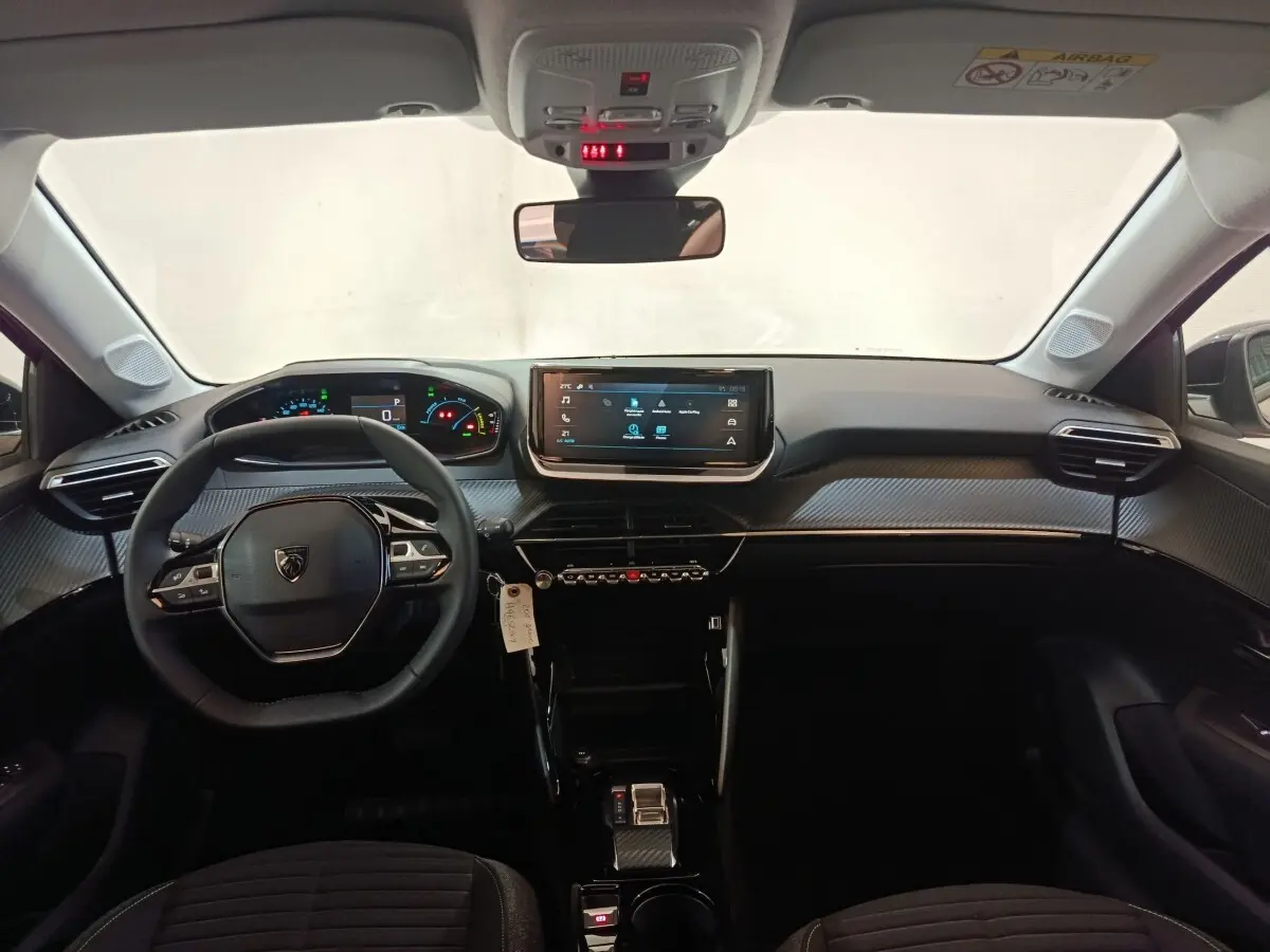 Vue intérieure frontale du tableau de bord et volant cuir de la Peugeot 208 électrique gris clair 2024.