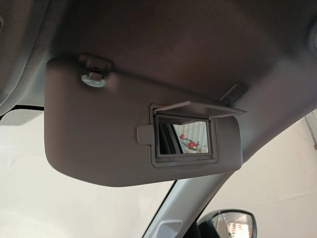 Détail du pare-soleil côté conducteur avec miroir de courtoisie ouvert dans une Peugeot 208 électrique gris clair.