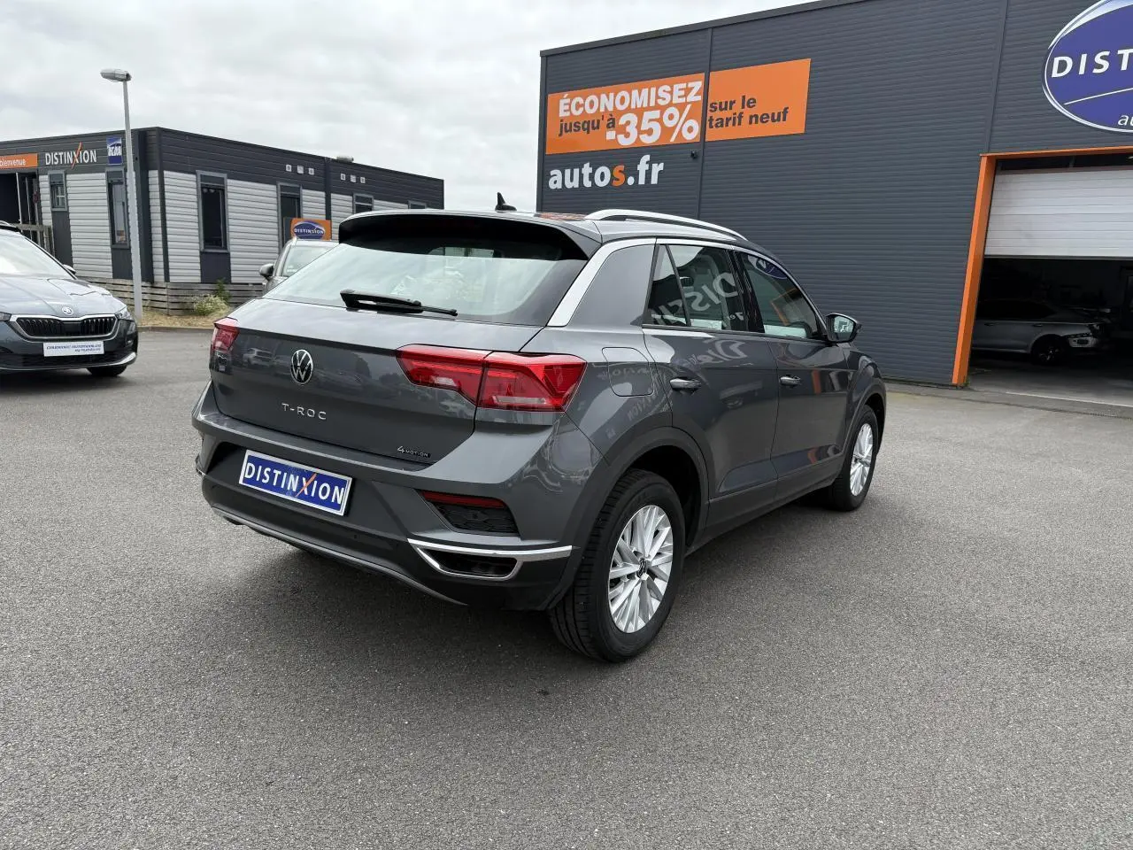 Volkswagen T-Roc gris Indium métal vu de l'arrière droit, avec détails chromés et feux arrière allongés.