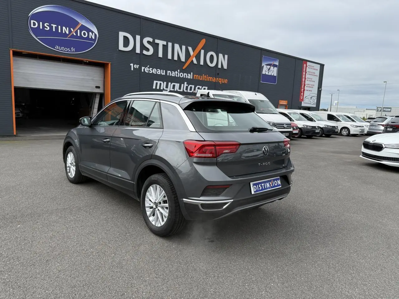 Volkswagen T-Roc gris Indium métal vu en 3/4 arrière droit sur parking devant concession Distinxion.