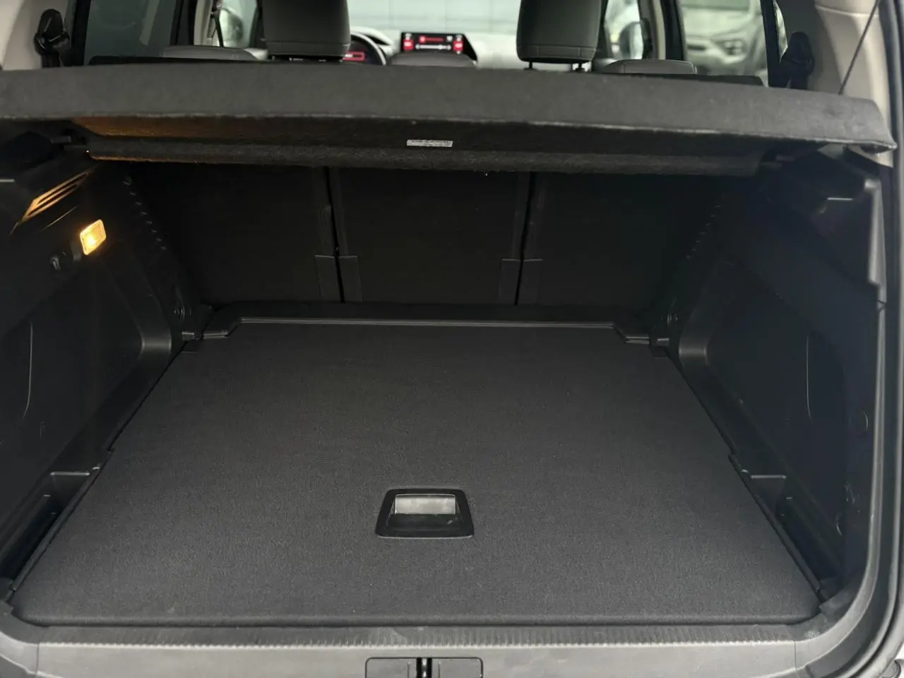 Coffre ouvert vu de l'arrière du Citroën C5 Aircross Hybrid gris Artense avec plancher modulable et habillage noir.