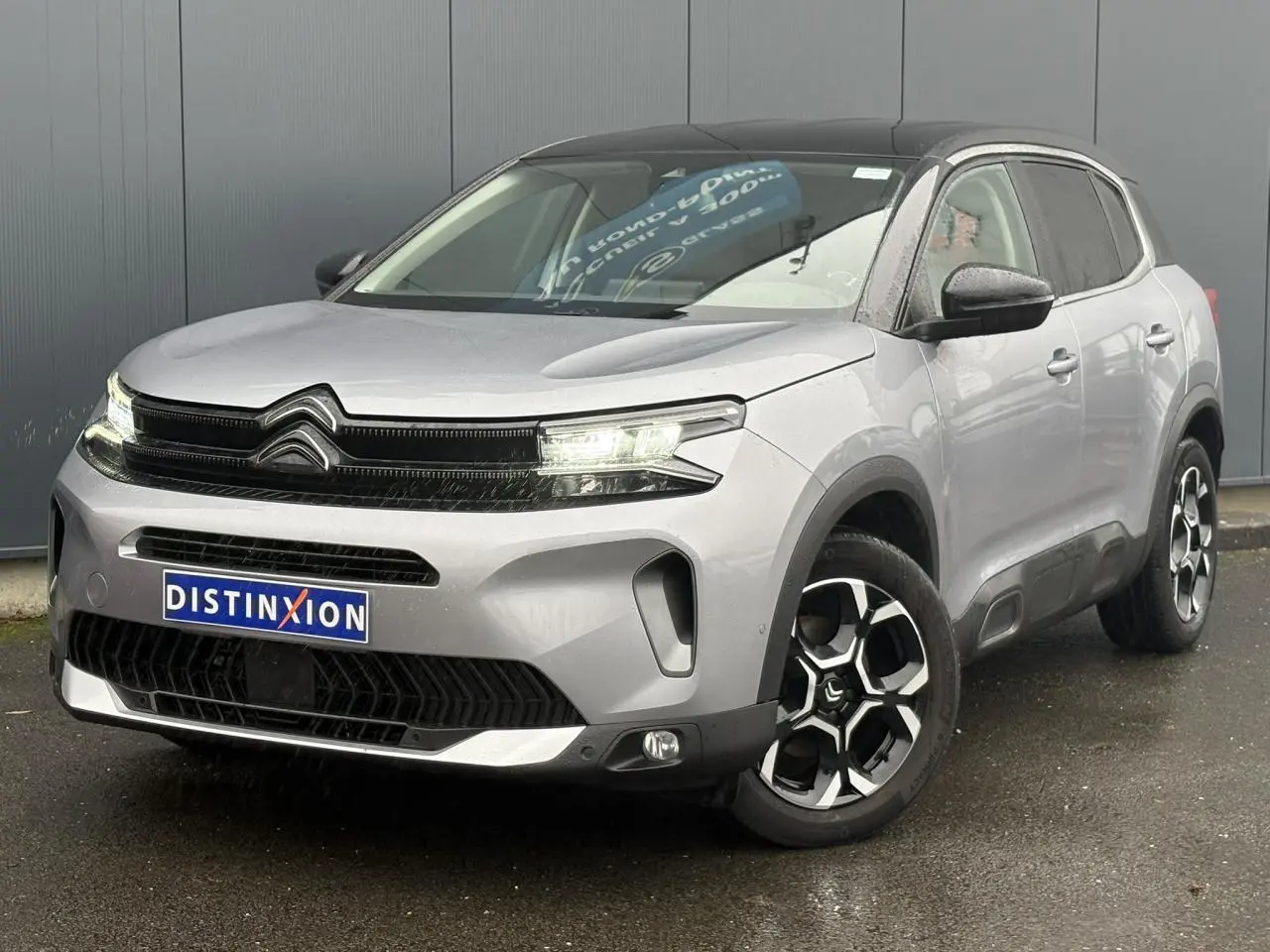 Vue 3/4 avant droite d'un Citroën C5 Aircross Hybrid gris Artense avec toit noir et jantes alliage 18 pouces.