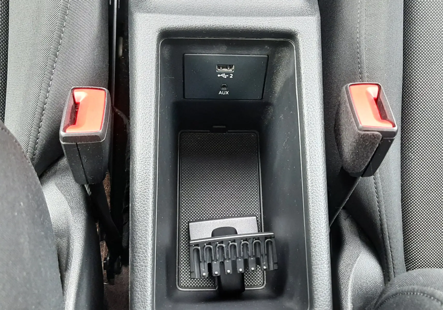 Vue en plongée sur la console centrale noire avec port USB et deux boucles de ceinture dans l'Audi Q2 2023.