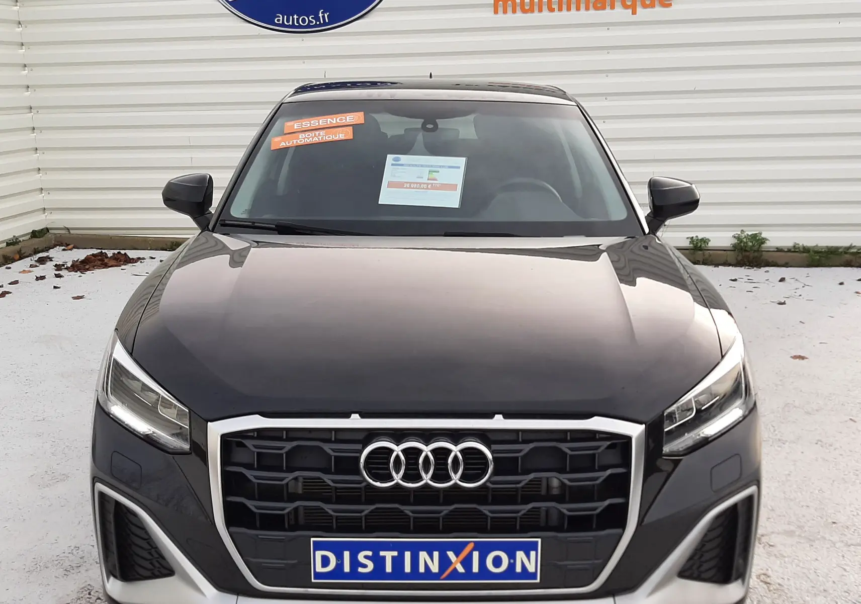 Vue frontale d'un Audi Q2 35 TFSI S-Line noir mito metal avec calandre hexagonale et phares LED allumés.