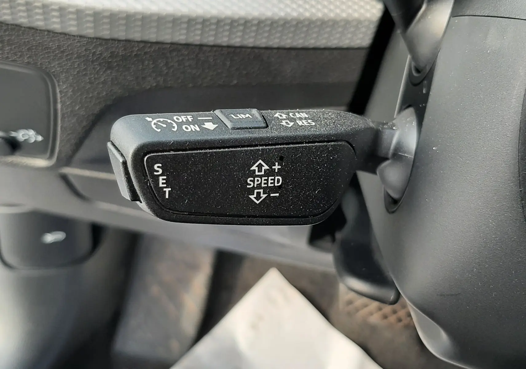 Gros plan sur le levier de régulateur de vitesse noir à gauche du volant de l'Audi Q2 35 TFSI 2023 noir mito metal.