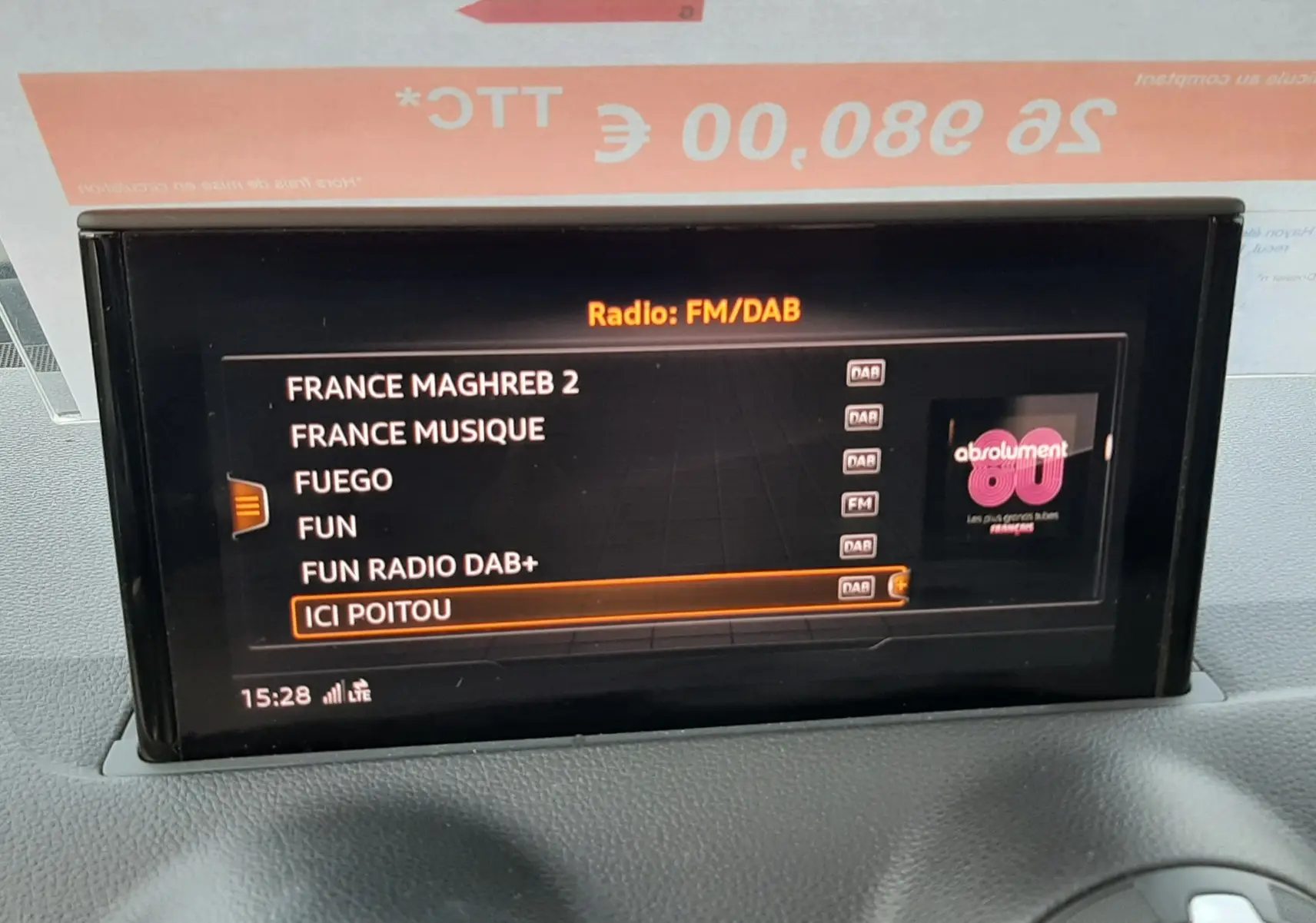 Écran central de l'Audi Q2 35 TFSI S-Line 2023 affichant les stations radio FM/DAB, avec tableau de bord noir texturé.