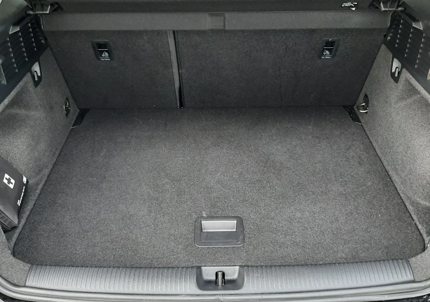 Coffre ouvert vu de l'arrière d'un Audi Q2 noir mito metal, espace de chargement propre et vide.