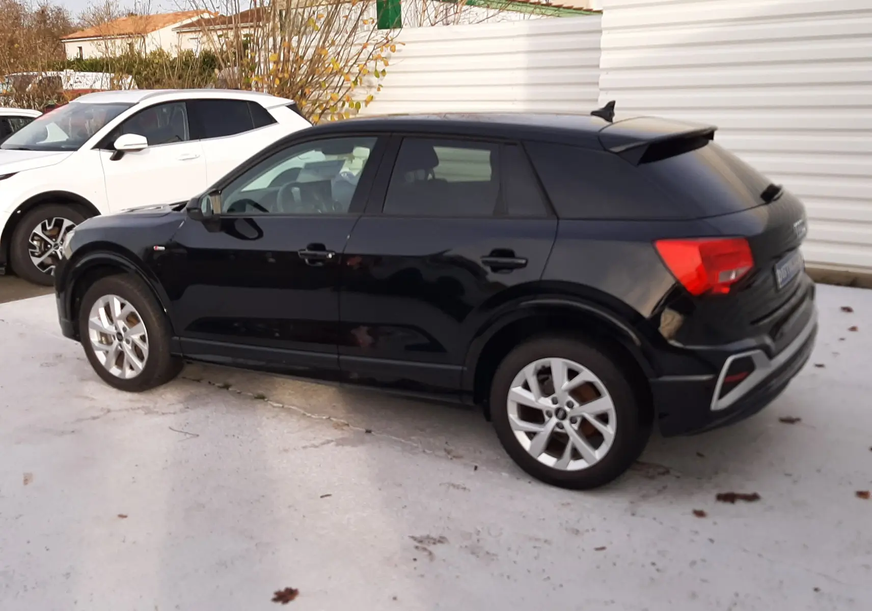 Audi Q2 noir mito metal vue de profil côté gauche, mettant en valeur ses lignes compactes et ses jantes argentées.
