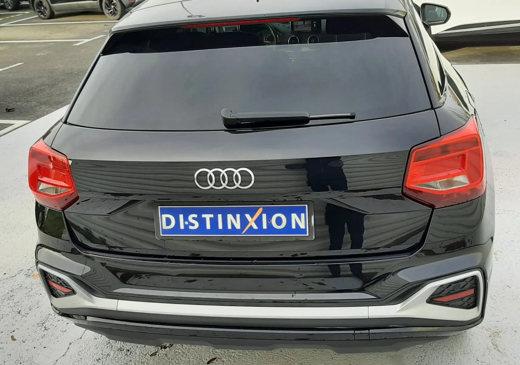 Vue arrière d'un Audi Q2 noir mito metal 2023 avec feux rouges et plaque d'immatriculation Distinxion visible.
