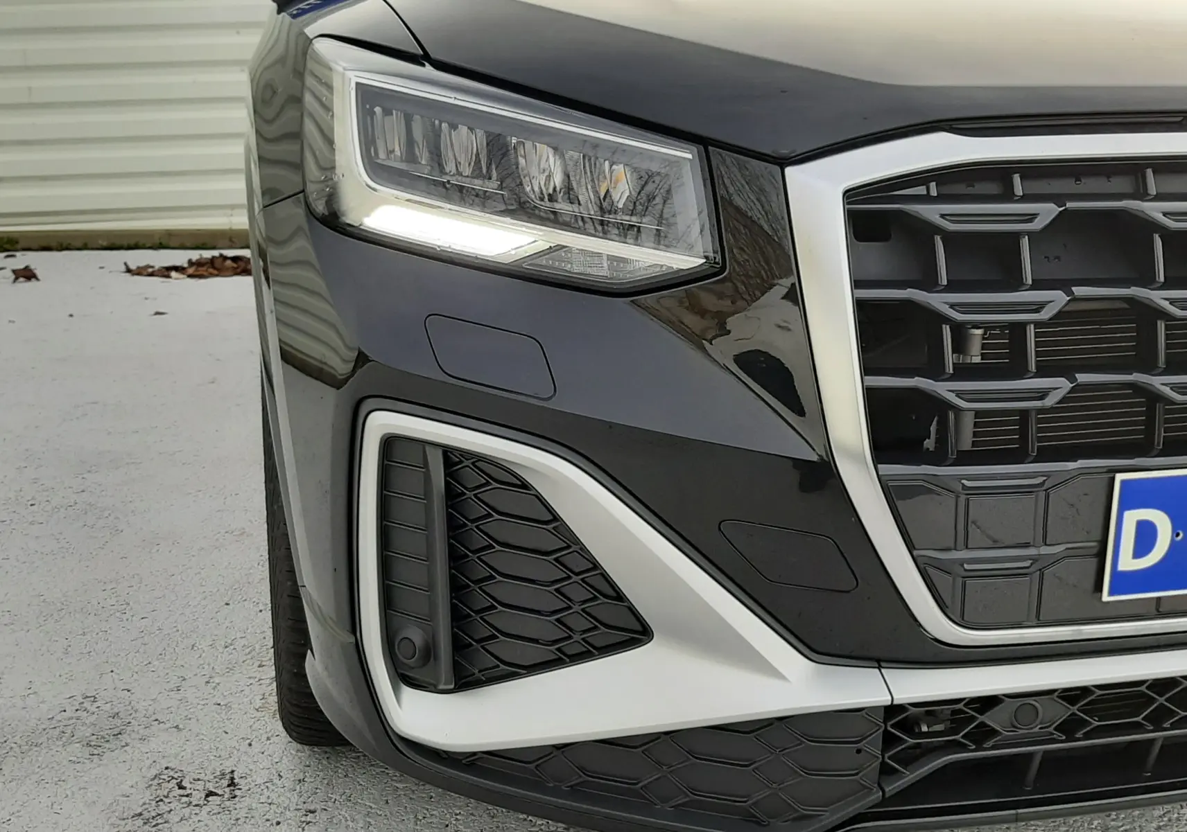 Gros plan sur l'avant gauche noir mito metal de l'Audi Q2 35 TFSI S-Line avec calandre et phares LED distinctifs.