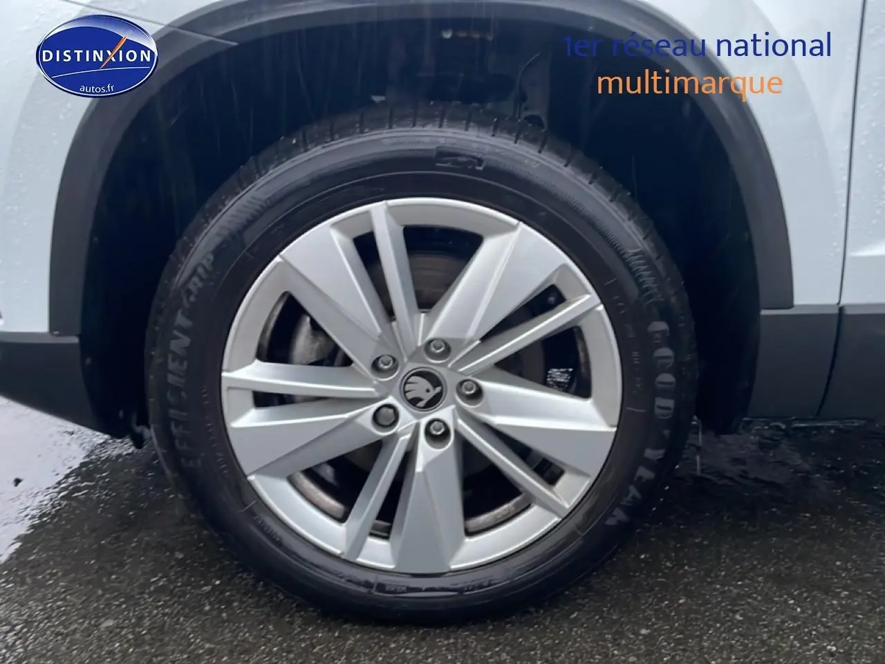 Gros plan sur la roue avant droite avec jante alu argentée du Skoda Karoq blanc glacial 2025.