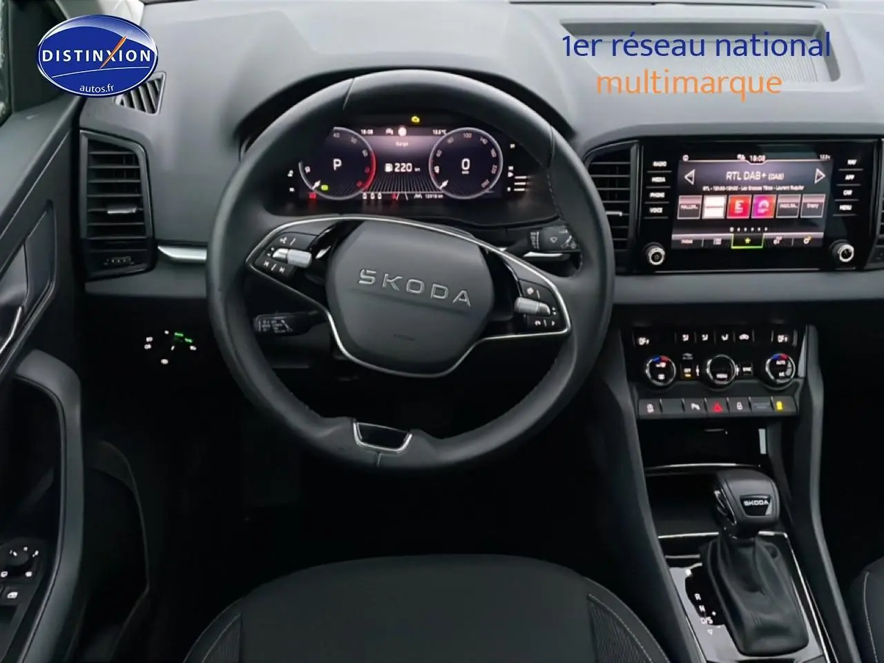Vue intérieure centrée sur le volant et la console centrale du Skoda Karoq 2025, avec écran tactile et levier de vitesse noir.