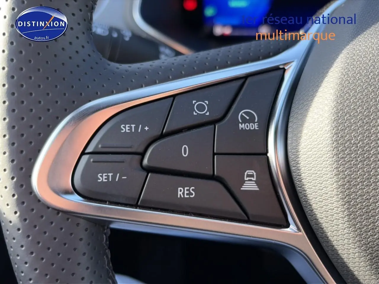 Gros plan sur les commandes du volant perforé gris clair de la Renault Symbioz 2026, boutons de régulateur de vitesse visibles.