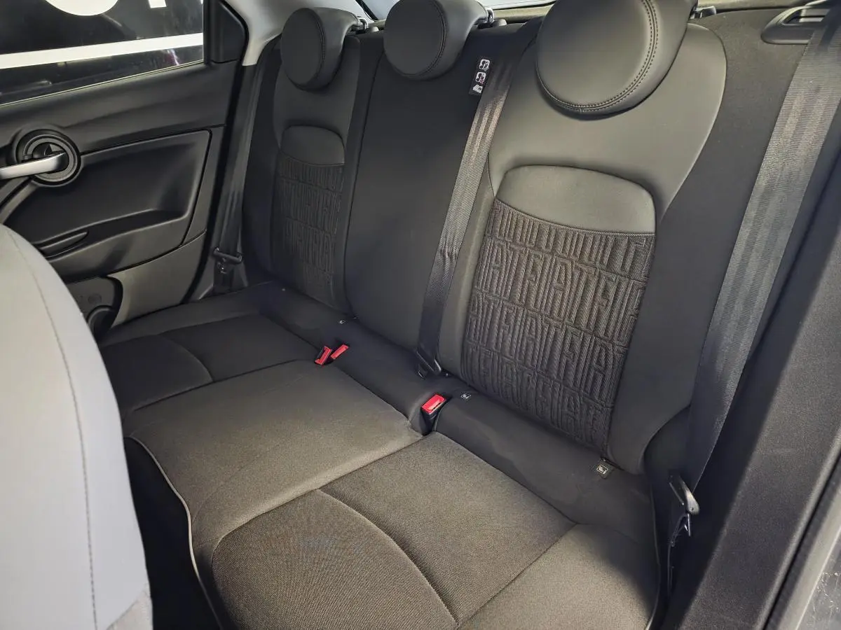 Vue intérieure sur les sièges arrière noirs avec monogramme FIAT du Fiat 500X gris, côté droit visible.