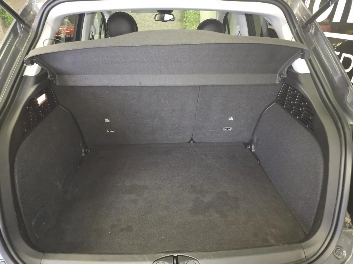 Coffre ouvert vu de l'arrière du Fiat 500X gris, montrant un espace de chargement propre et spacieux.