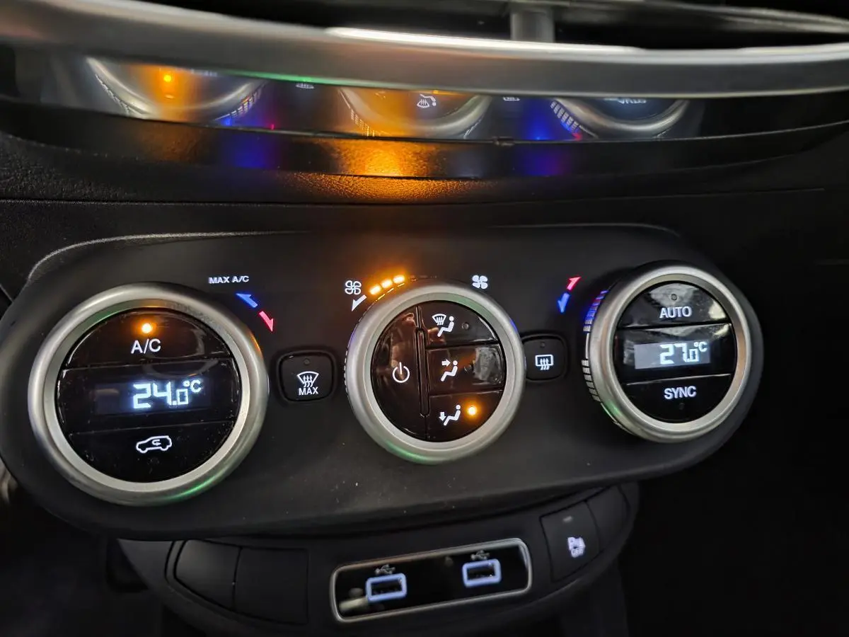 Gros plan sur la console centrale de la Fiat 500X 2024, montrant les commandes de climatisation automatique bi-zone et ports USB arrière.