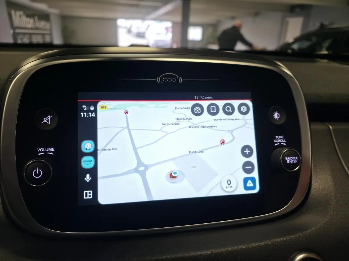 Écran tactile central avec navigation GPS allumée dans le tableau de bord d'une Fiat 500X gris 2024.