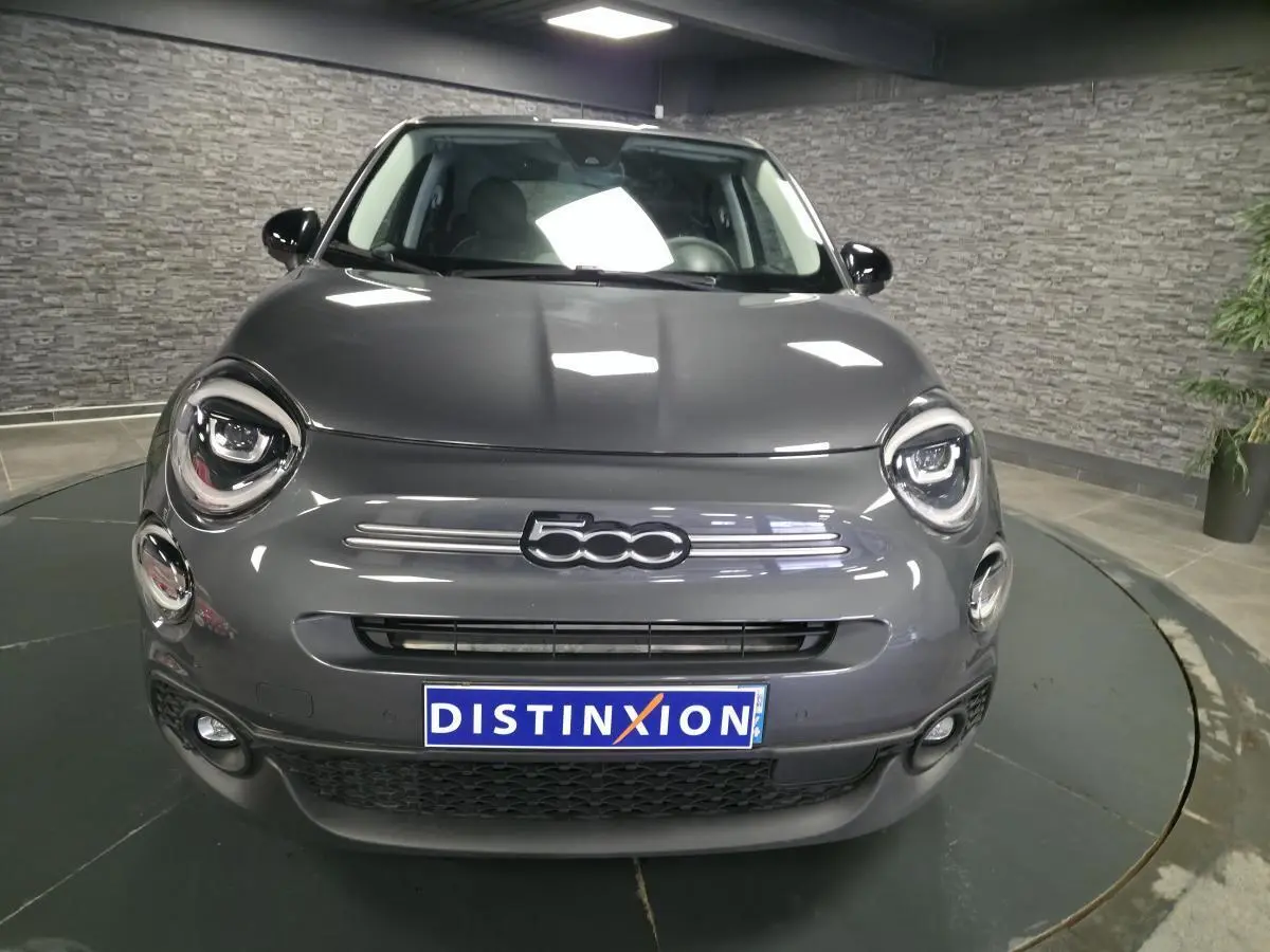Vue avant d'une Fiat 500X gris métallisé avec phares LED et logo 500 bien visible sur fond intérieur gris.