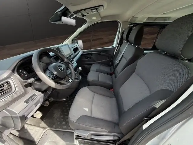 Vue intérieure côté conducteur du Renault Trafic Fourgon gris clair 2022, montrant les sièges avant et le volant multifonctions.