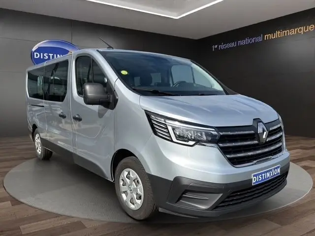 Vue 3/4 avant droit d’un Renault Trafic Fourgon gris clair avec calandre noire et feux LED, en intérieur showroom.