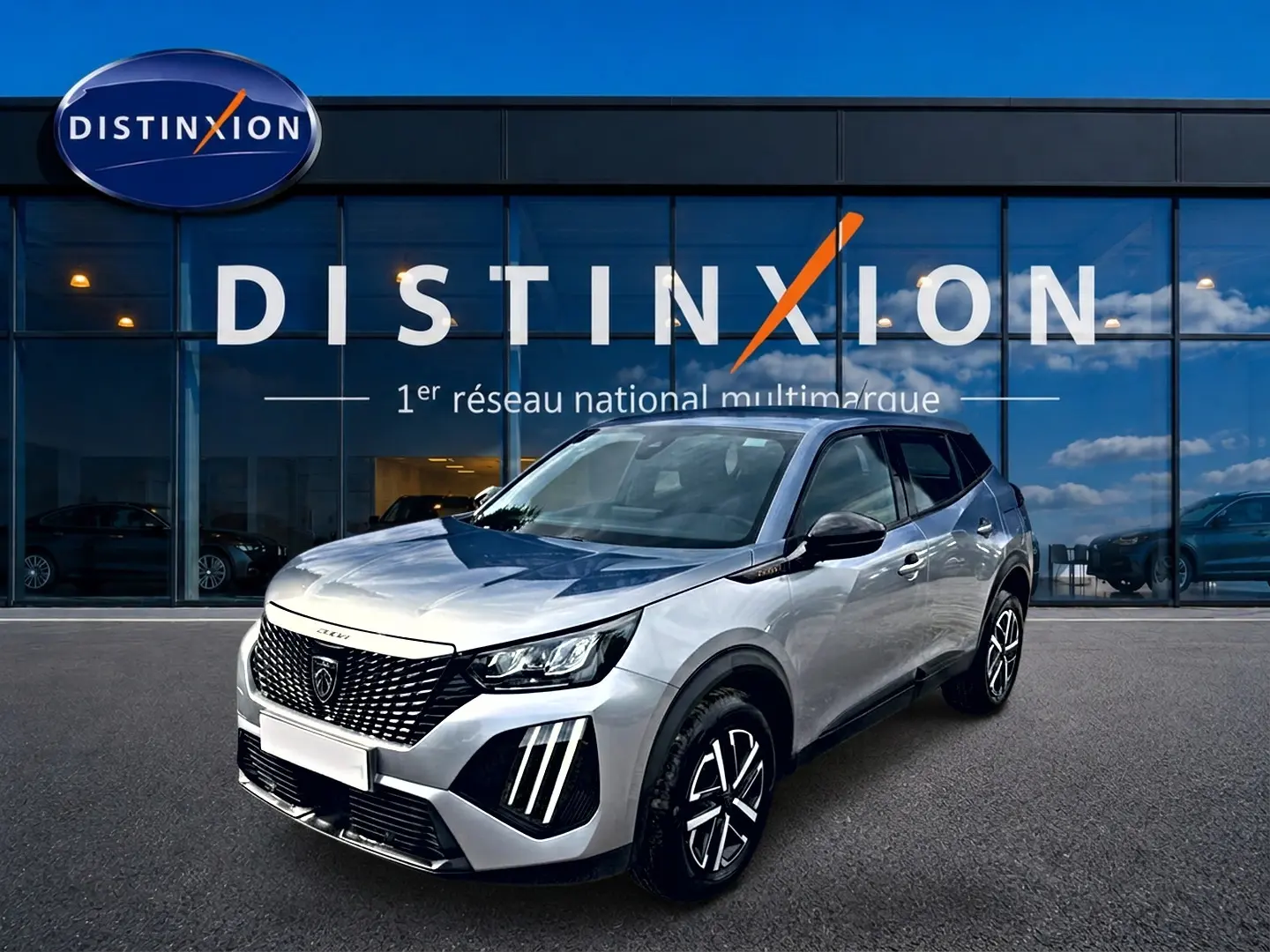 Peugeot 2008 gris en 3/4 avant droit, avec calandre noire et feux LED distinctifs, devant une vitrine Distinxion.