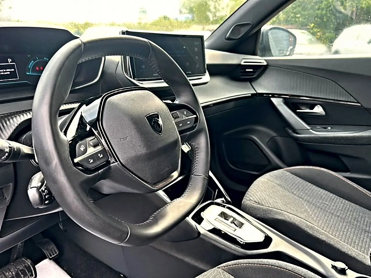 Intérieur de la Peugeot 2008 1.2 hybrid 145 style e-dcs6 2025, vue côté conducteur sur volant et console centrale noire.
