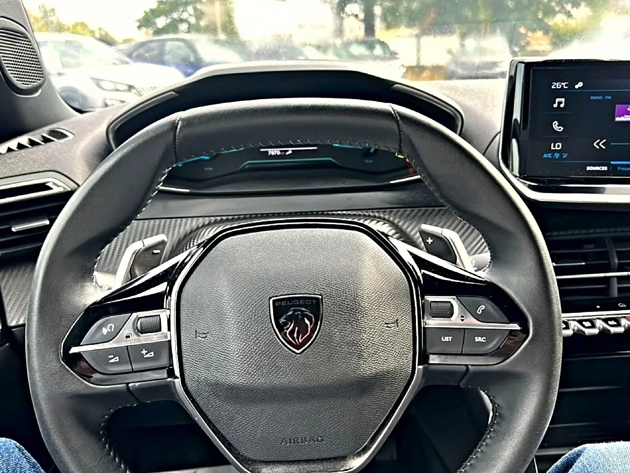 Vue centrée sur le volant multifonction noir du Peugeot 2008 1.2 hybrid 145 style avec tableau de bord et écran tactile.