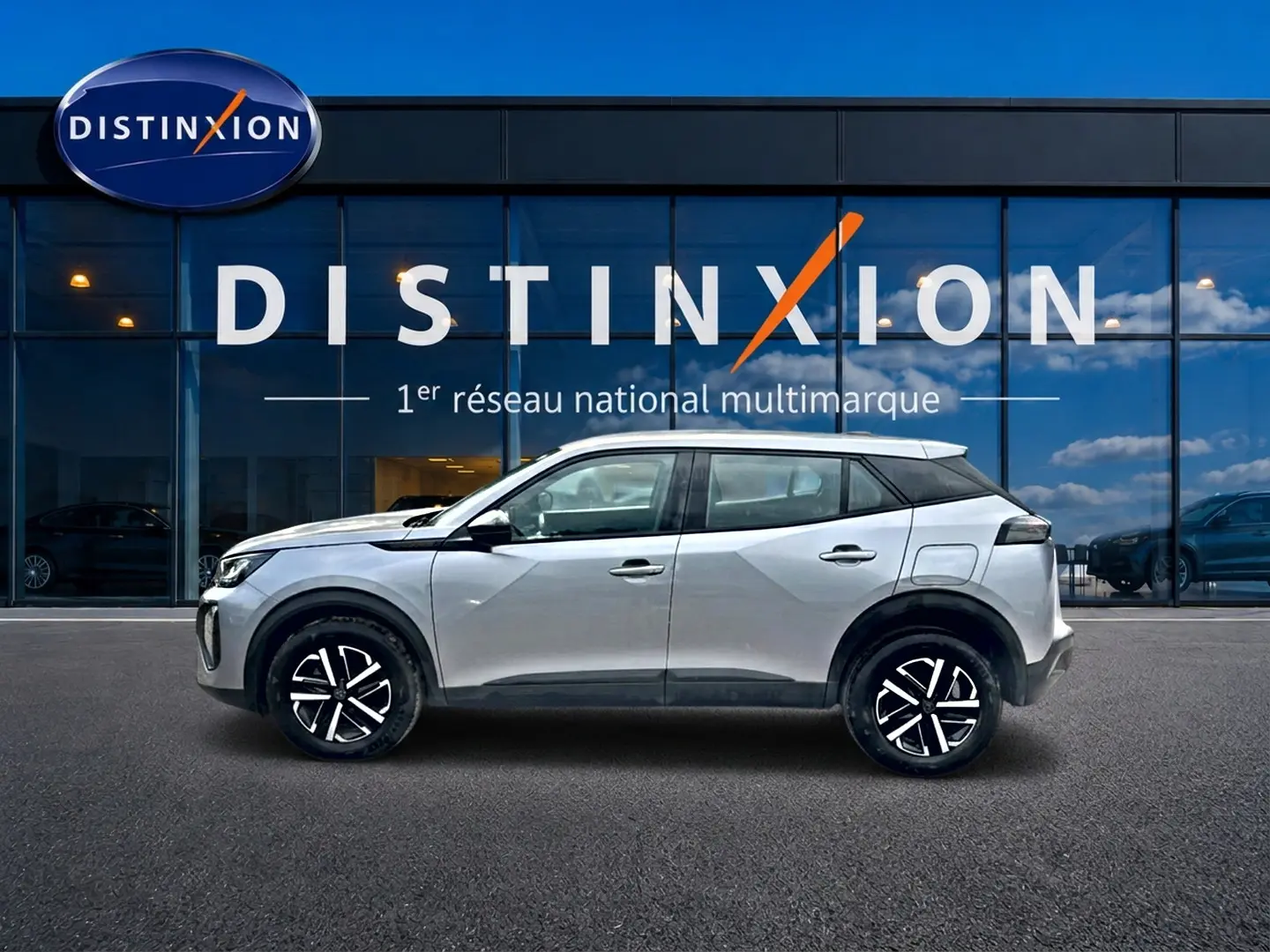 Profil droit d’un Peugeot 2008 gris 2025 avec toit noir et jantes modernes devant une vitrine Distinxion.
