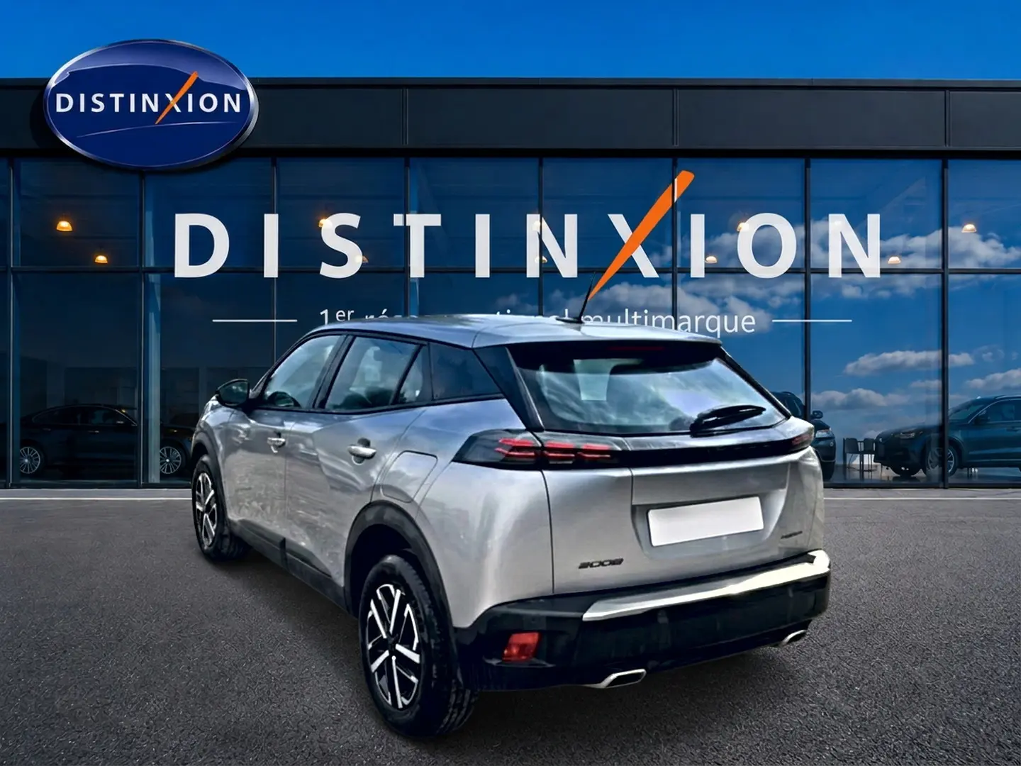 Peugeot 2008 gris 3/4 arrière droit, avec feux arrière LED et becquet, stationné devant une vitrine Distinxion.