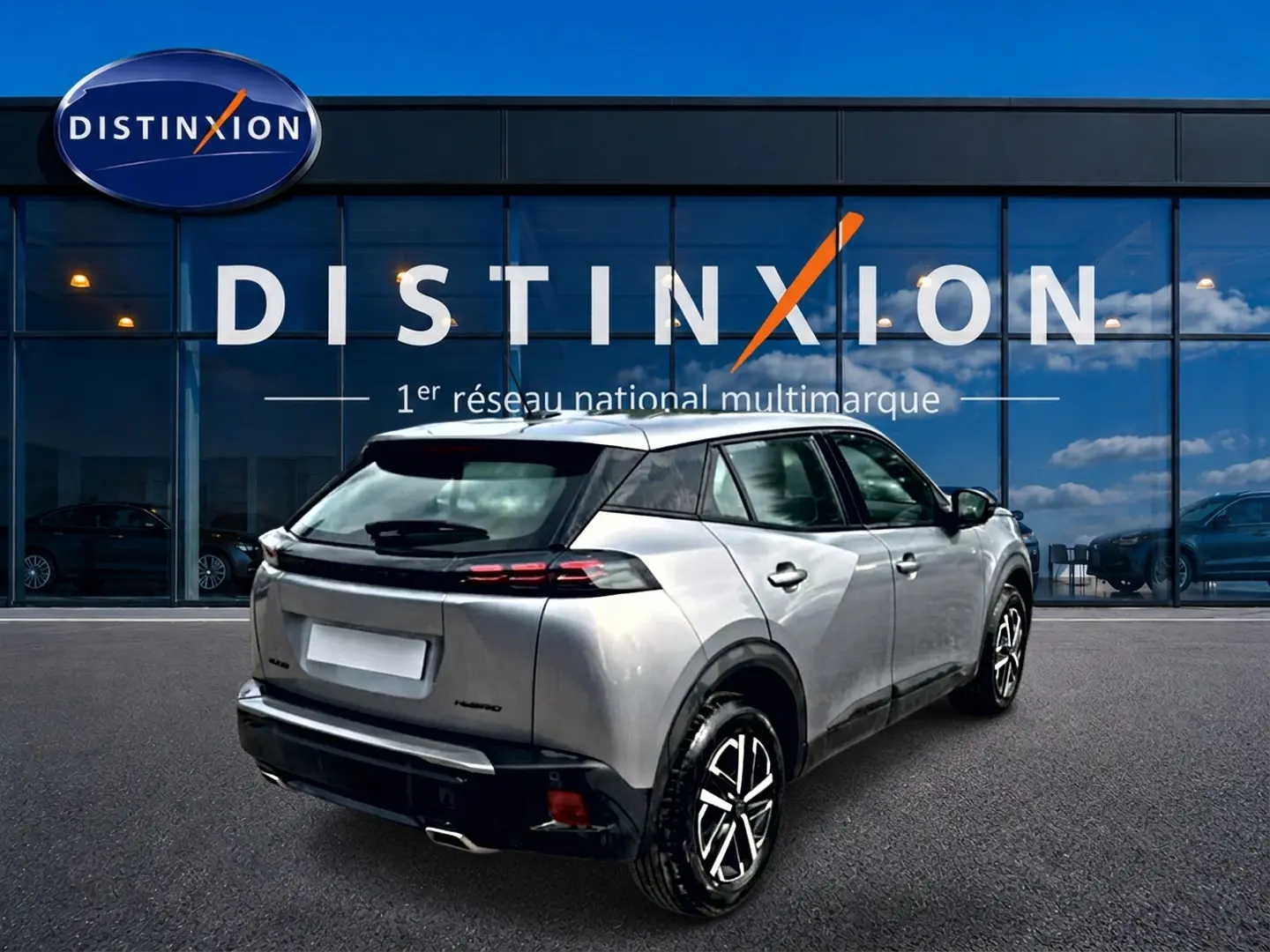 Vue 3/4 arrière droite d'un Peugeot 2008 gris 2025 avec toit noir et feux arrière LED, devant une vitrine Distinxion.