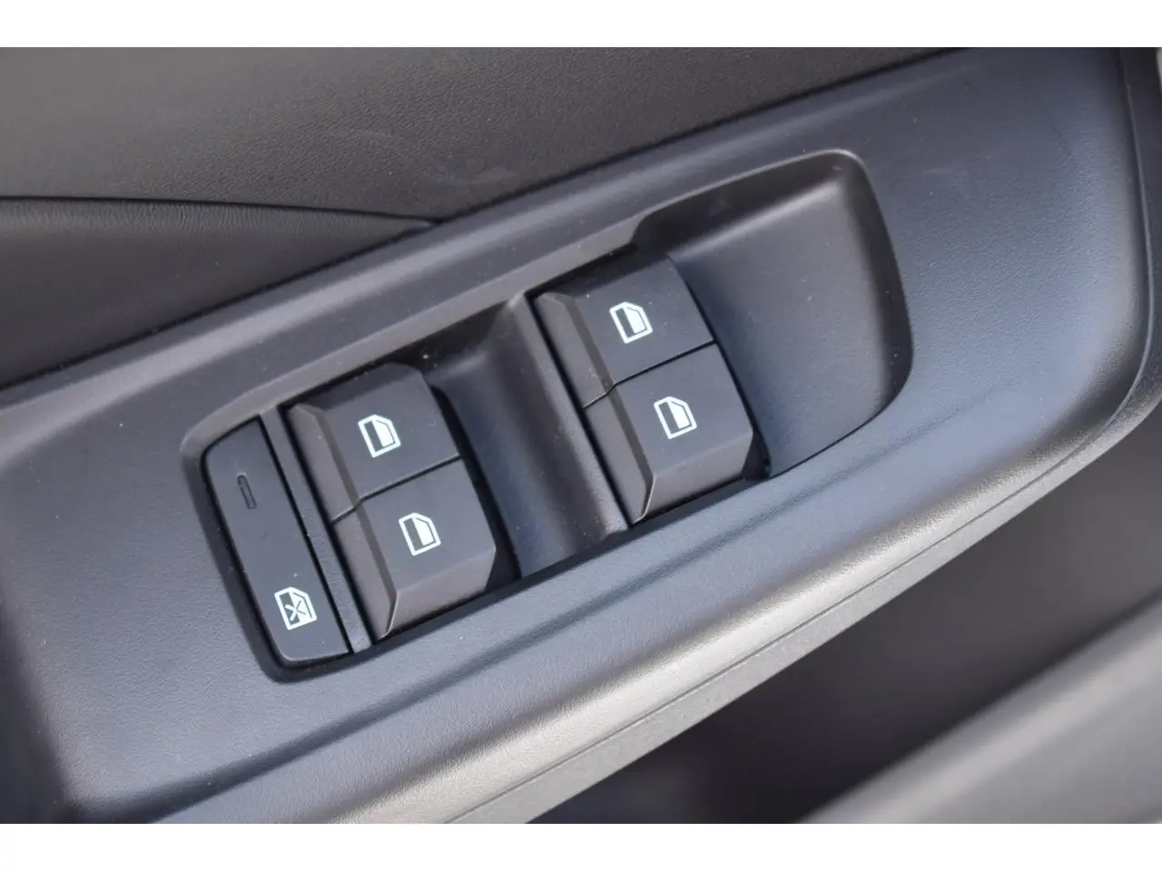 Gros plan sur les commandes des vitres électriques côté gauche de la porte d'une MG3 blanche 2026.