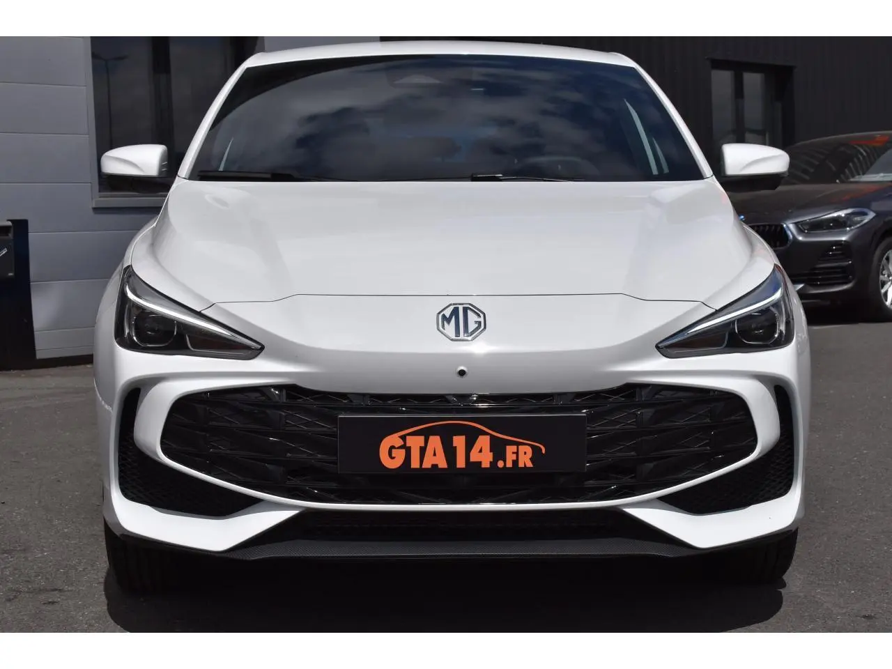 Vue avant d'une MG3 blanche 2026 avec calandre noire et phares LED anguleux, stationnée en extérieur.