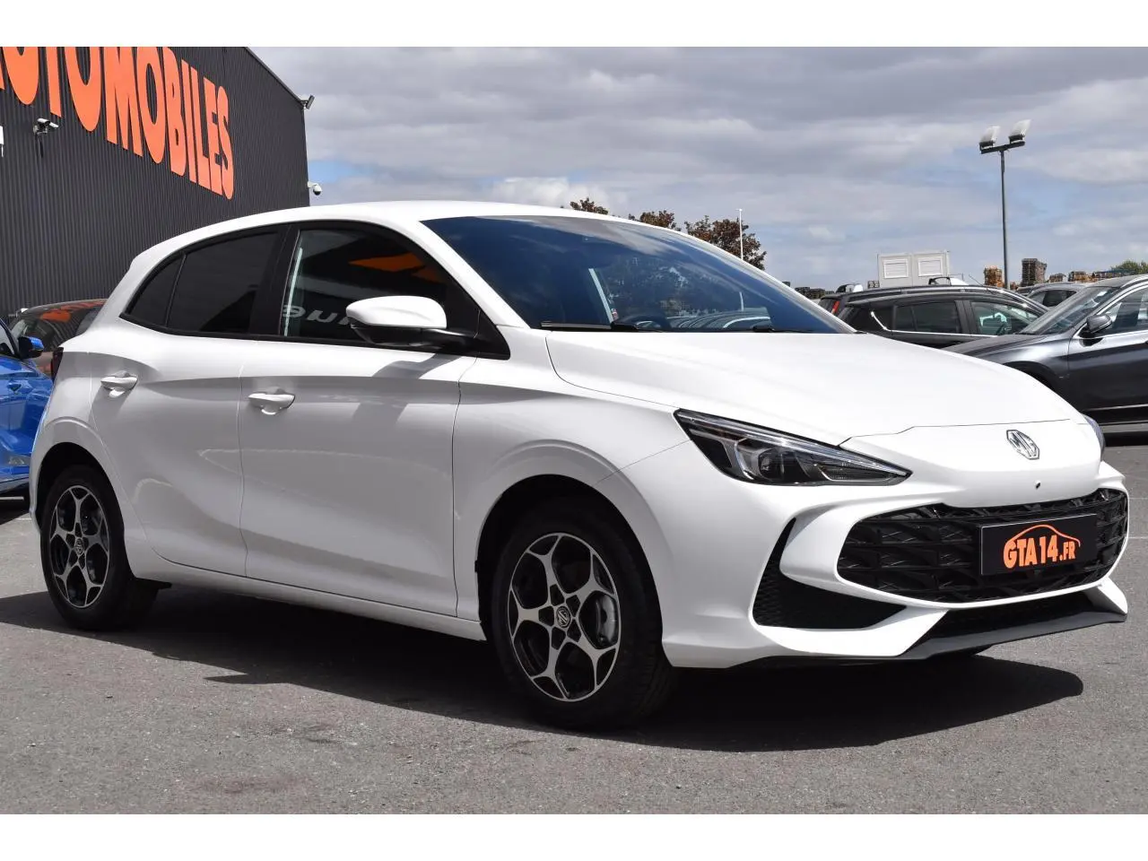 MG3 blanc en vue 3/4 avant droit, avec jantes alliage distinctives et calandre noire sportive.