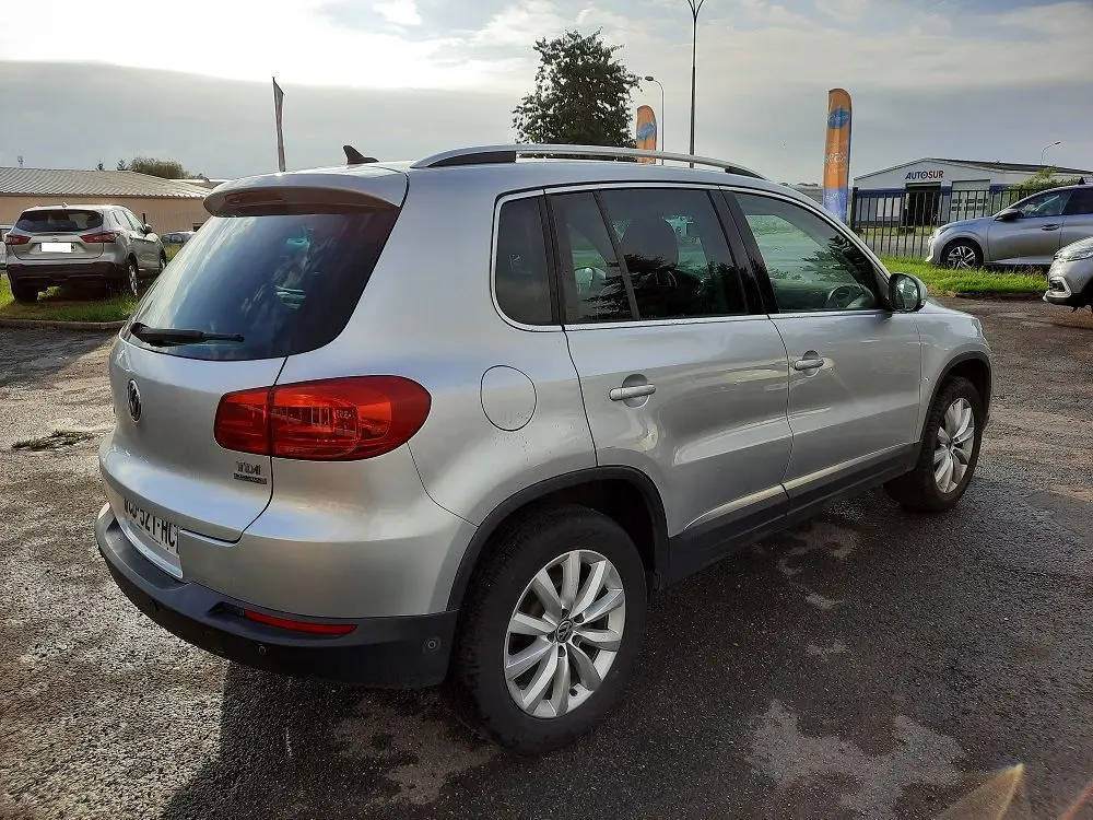 Volkswagen Tiguan 2.0 TDI gris argent vu en 3/4 arrière droit, avec feux arrière rouges et jantes alliage 17 pouces.