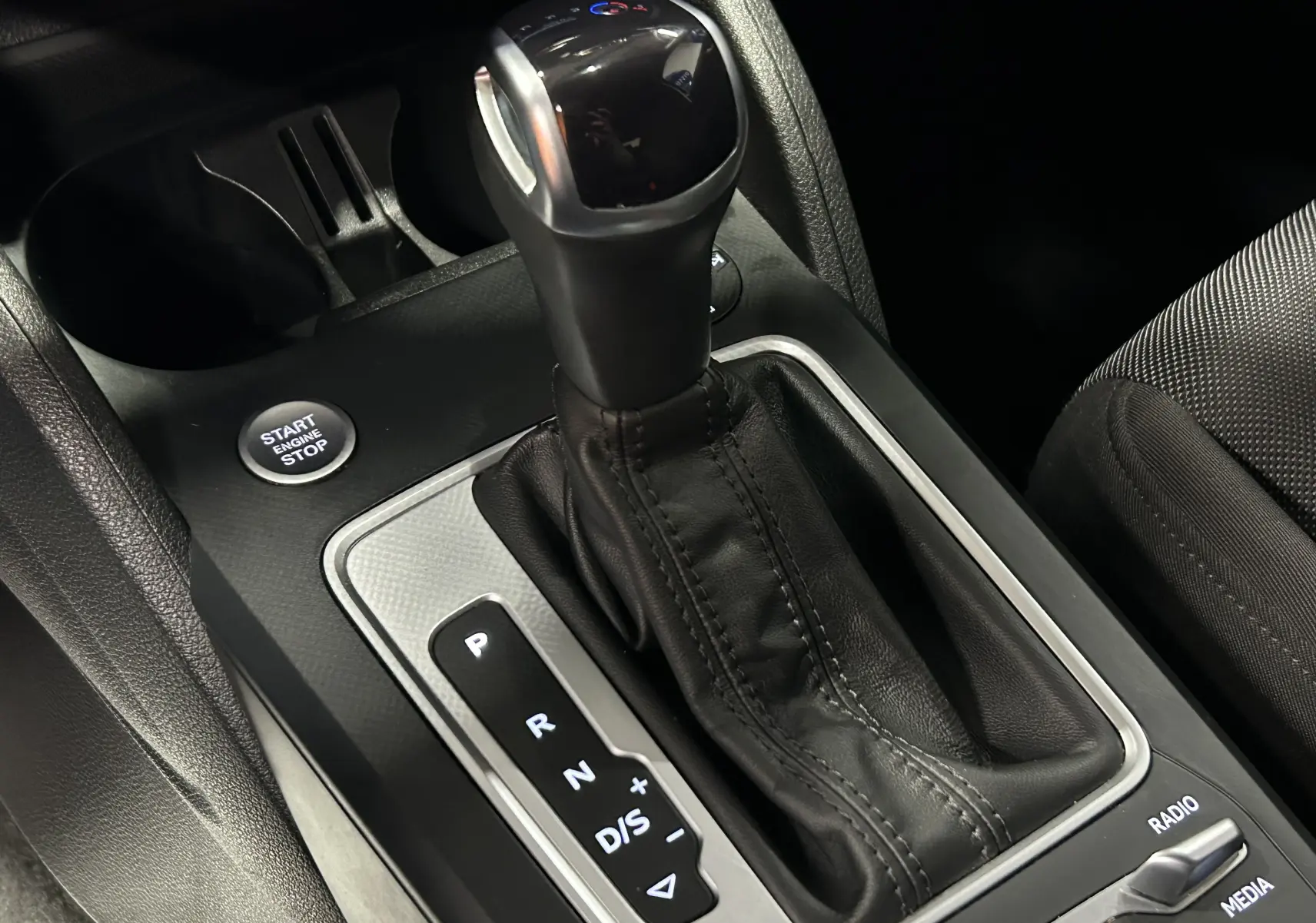 Gros plan sur les boutons de commande du frein à main électrique et de l'arrêt automatique dans l'Audi Q2 noir métal 2023.