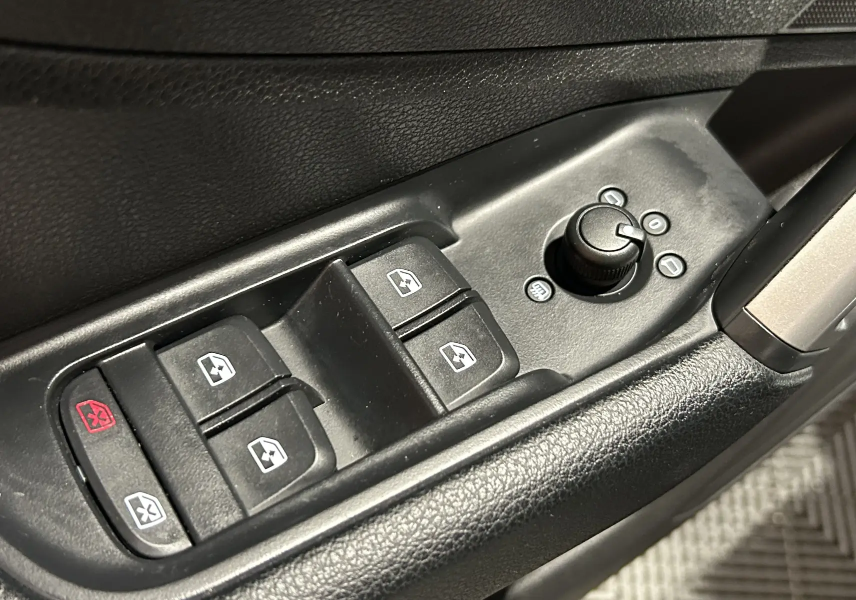 Gros plan sur la plaque de seuil de porte éclairée avec logo S de l'Audi Q2 noir métal, côté conducteur intérieur.