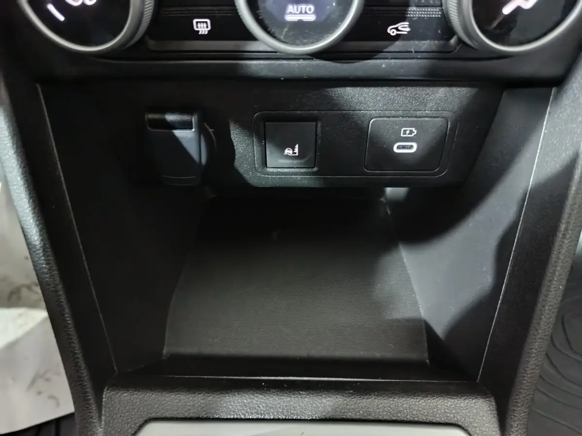 Gros plan sur la console centrale noire de la Dacia Sandero Extreme+ 2024, avec prise USB-C et bouton de siège chauffant.