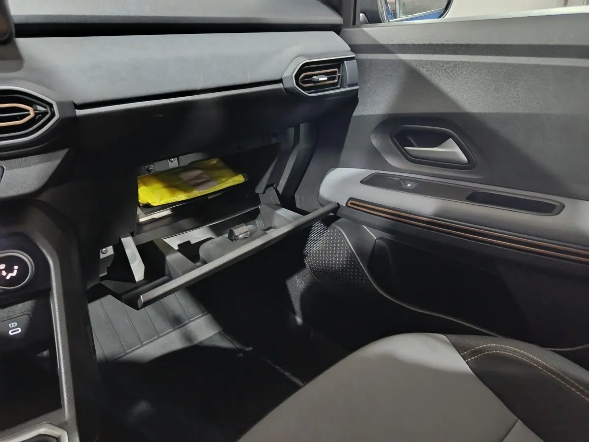 Vue intérieure côté passager du tableau de bord et boîte à gants ouverte de la Dacia Sandero Extreme+ TCe 110 bleu 2024.