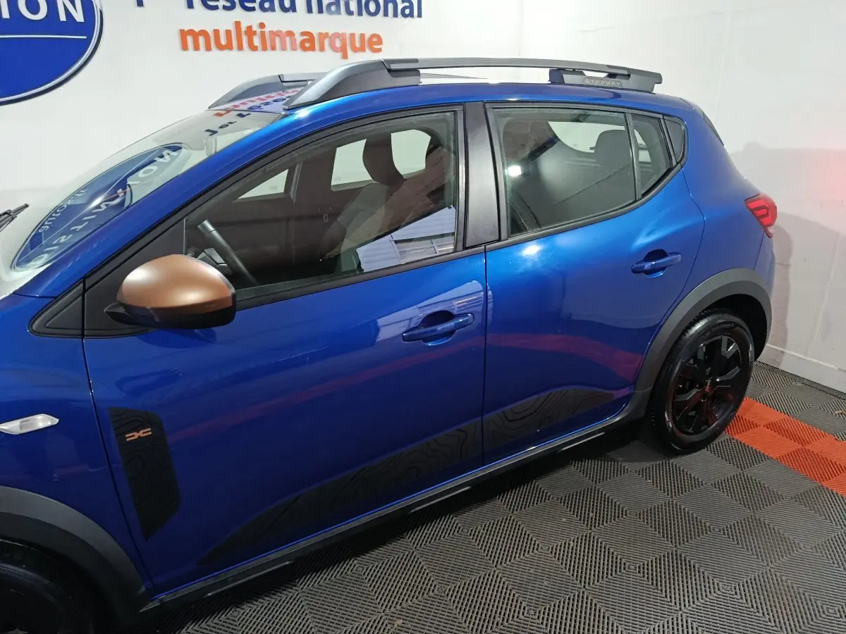 Vue de profil côté gauche d'une Dacia Sandero Extreme+ bleu avec rétroviseurs bronze et jantes noires.