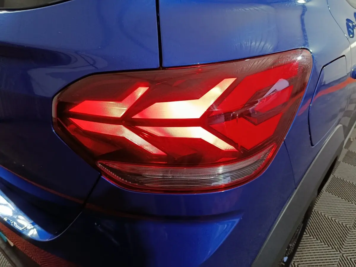 Gros plan sur le feu arrière droit rouge du Dacia Sandero Extreme+ bleu 2024, soulignant la carrosserie brillante.
