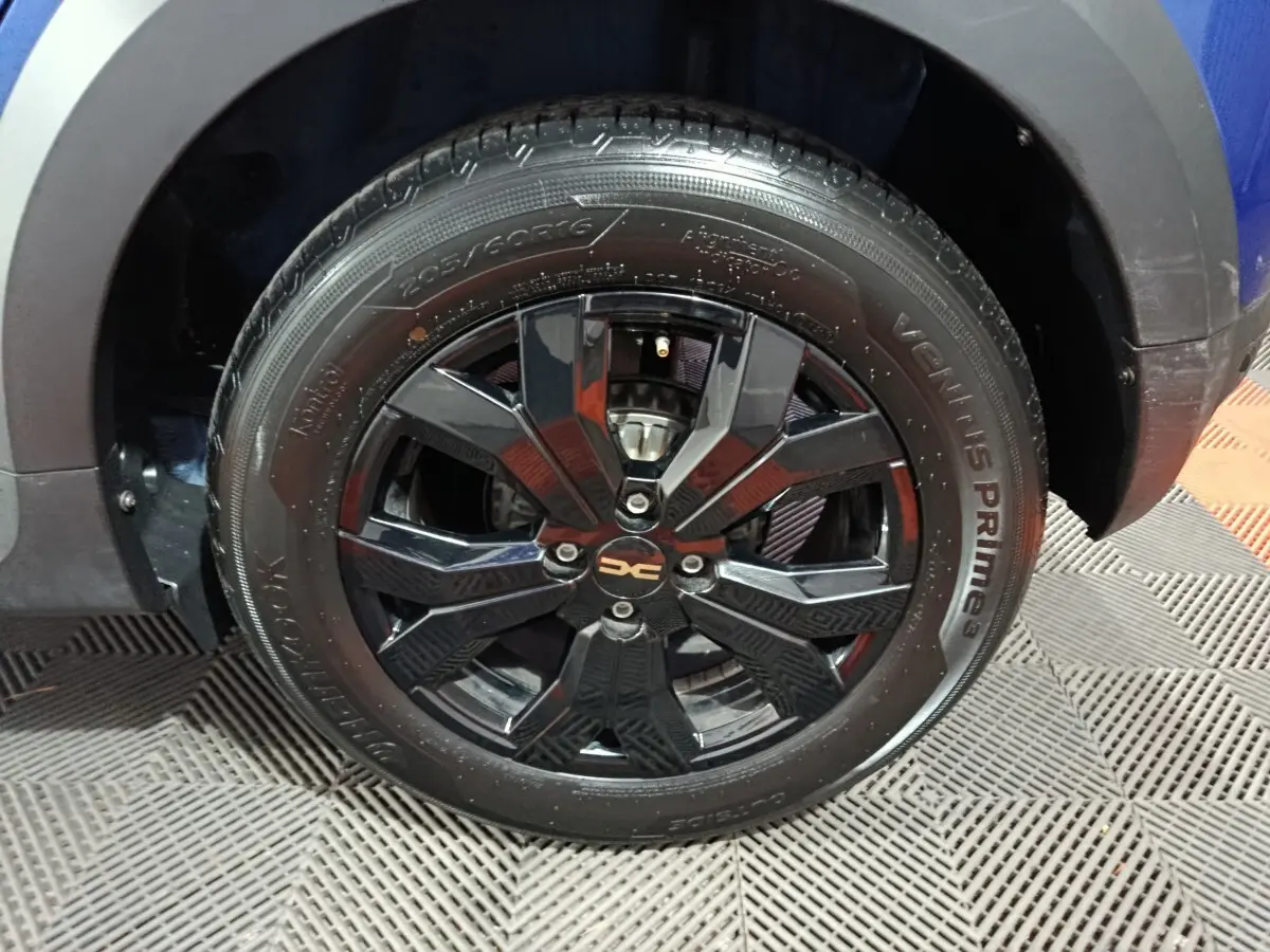 Gros plan sur la roue avant droite noire brillante d'une Dacia Sandero Extreme+ bleu 2024.