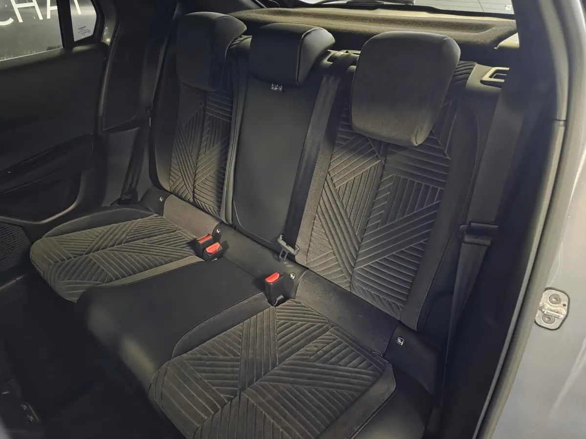 Vue intérieure arrière des sièges en velours gris anthracite de la Lancia Ypsilon 2025, avec ceinture de sécurité et portière ouverte.