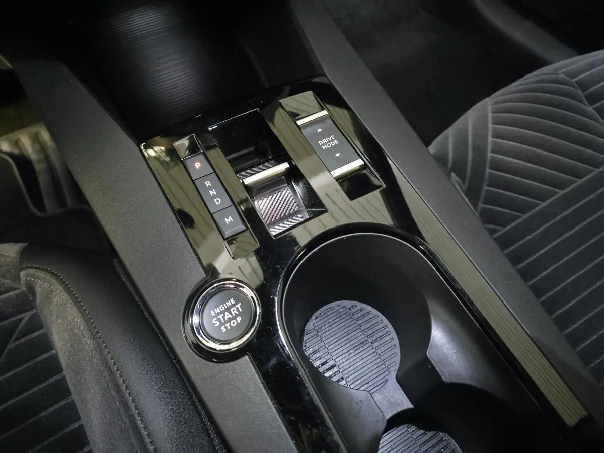 Vue rapprochée de la console centrale noire brillante avec bouton start/stop et levier de boîte automatique sur Lancia Ypsilon gris.