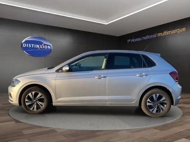 Vue latérale droite d'une Volkswagen Polo gris clair 2021, avec jantes alliage et vitres teintées, en intérieur showroom.