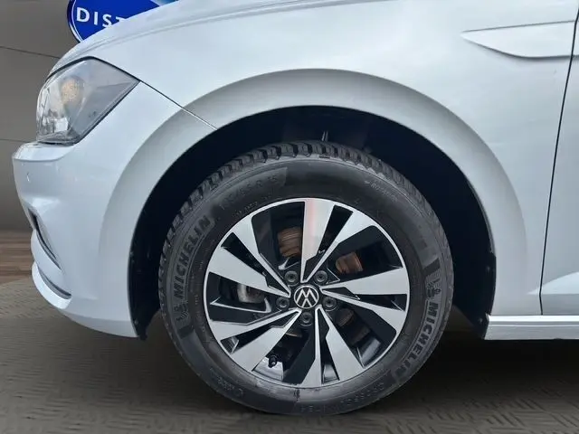 Vue de profil avant gauche sur une Volkswagen Polo gris clair, mettant en valeur le phare et la roue avant.