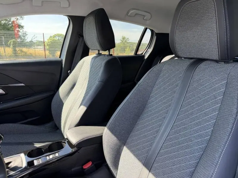 Vue intérieure rapprochée des sièges avant en tissu gris et noir de la Peugeot 208 1.2 100ch Allure 2025.