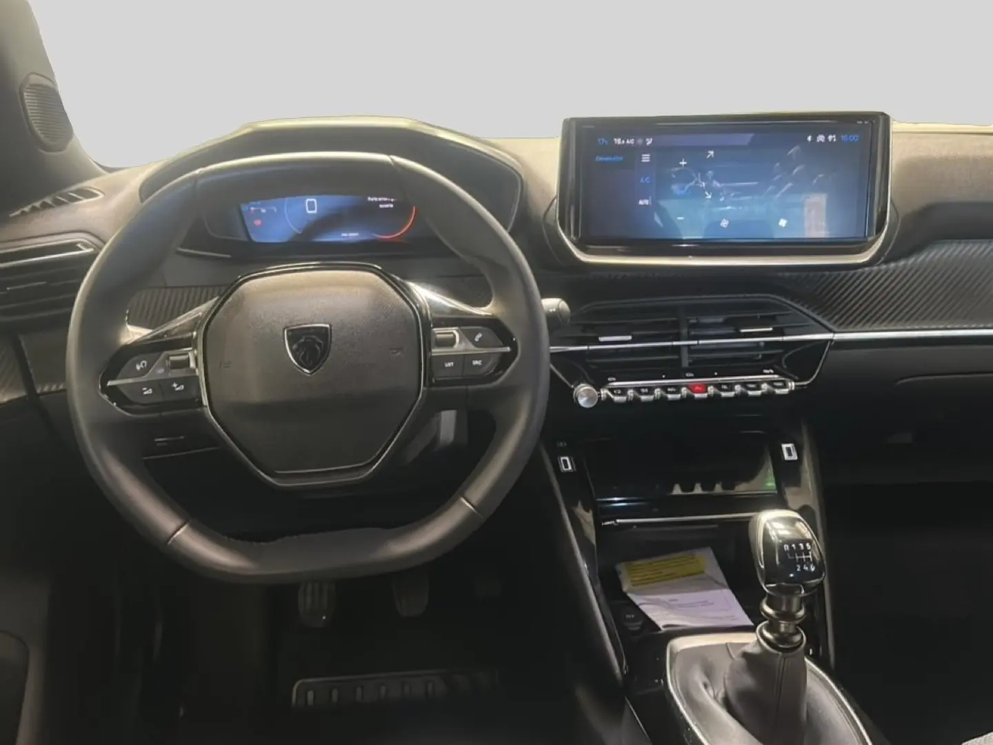 Vue intérieure frontale du tableau de bord et volant noir d'une Peugeot 2008 1.2 100 allure avec boîte manuelle.