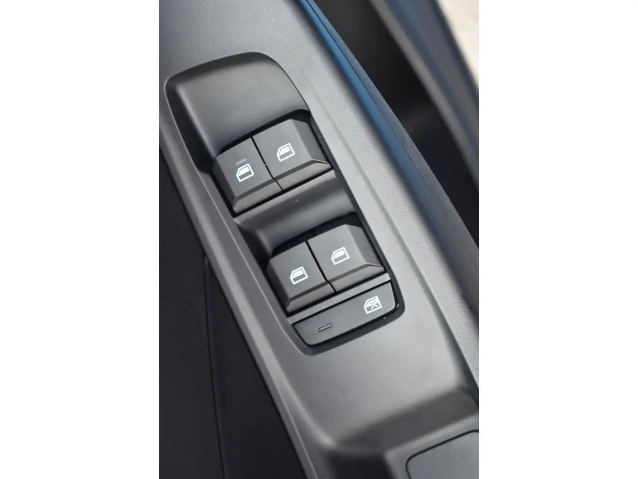 Gros plan sur les commandes des vitres électriques côté conducteur du MG3 1.5 L Hybrid+ 2026, intérieur noir.