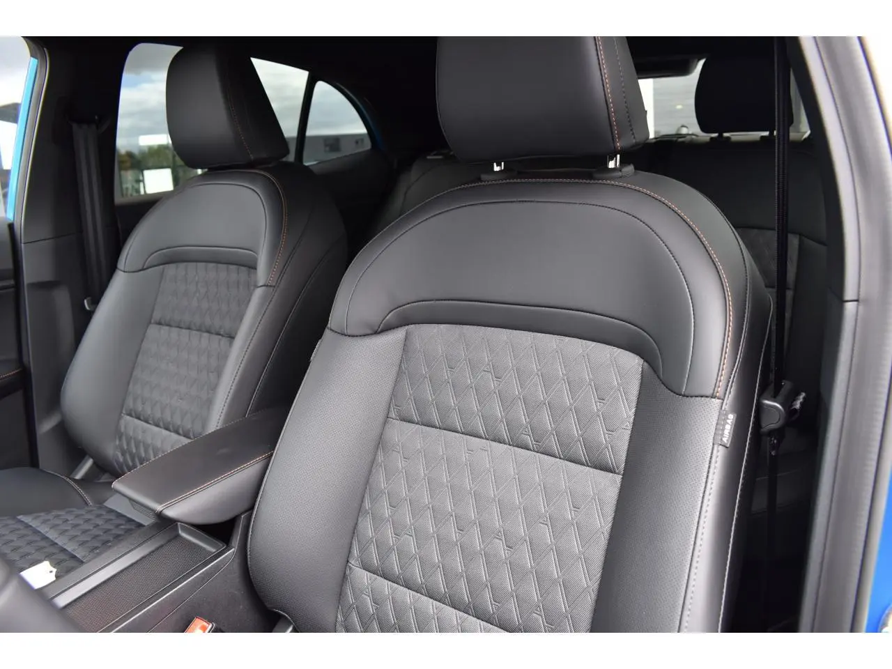 Gros plan sur les sièges avant en cuir noir avec surpiqûres orange du MG3 1.5 L Hybrid+ bleu, vue côté conducteur.