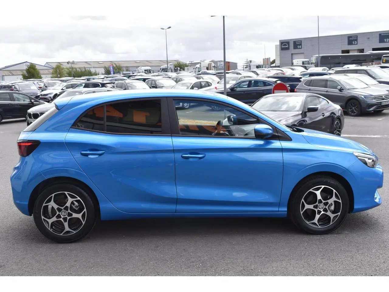 Vue de profil côté gauche d'une MG3 bleu métallisé avec jantes alliage et vitres surteintées sur parking.